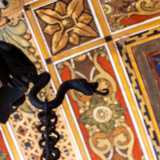 Dal centro pende un lampadario in ferro nero con piccoli serpenti, emblema massonico della salvezza